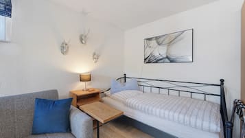 Une chambre à coucher avec un lit, une table de chevet, une lampe, un oreiller bleu, une table en bois et des têtes de cerf accrochées au mur.