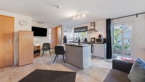 A modern kitchen with a central island, a dining area with a sofa and chairs, and a large sliding glass door to the outdoors. - Apartment Knodel No. 3 in Kraichgau – Quiet, Wi-Fi & Ideal for Business (Sachsenheim)