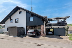 A two-story house with a garage, a covered porch, and a driveway. - Apartment Knodel No. 3 in Kraichgau – Terrace, Garden & Wi-Fi (Sachsenheim)