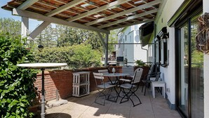 A covered patio with a table and chairs, a brick wall, and a view of a house. - Apartment Knodel No. 3 in Kraichgau – Quiet, Wi-Fi & Ideal for Business (Sachsenheim)