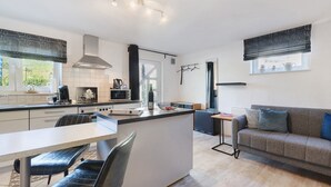 A modern kitchen with a central island, a dining area with a table and chairs, a sofa, and a window with curtains. - Apartment Knodel No. 3 in Kraichgau – Quiet, Wi-Fi & Ideal for Business (Sachsenheim)
