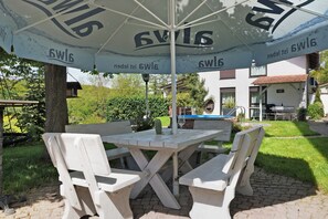 A wooden table with four chairs under a large umbrella with the text '6W16'. - Apartment Knodel No. 3 in Kraichgau – Terrace, Garden & Wi-Fi (Sachsenheim)