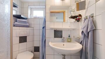 Un baño con inodoro, lavamanos, toallero y espejo.