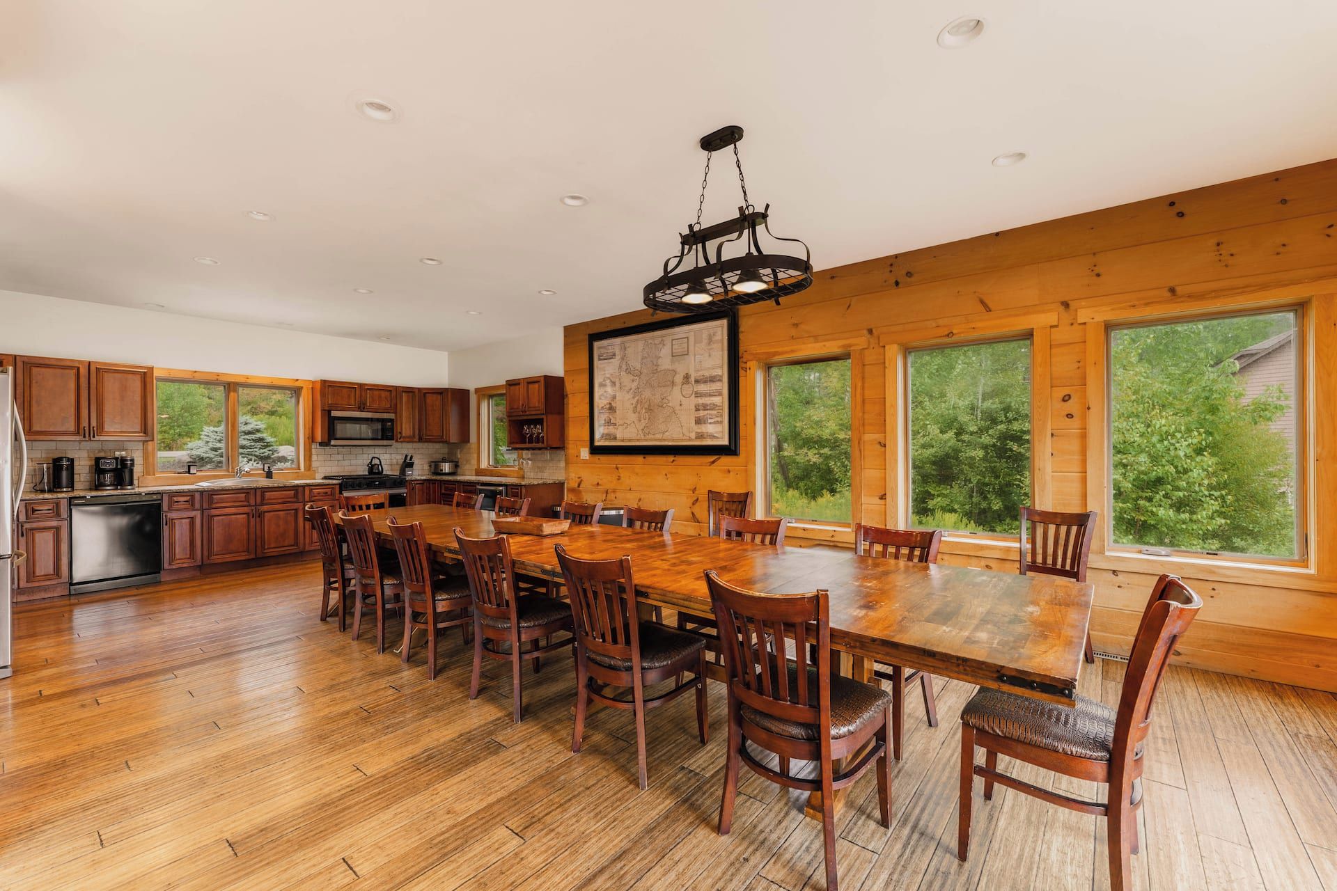 Une cuisine spacieuse avec des meubles en bois, une grande table à manger et un luminaire suspendu.