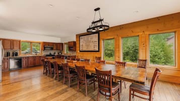 Une cuisine spacieuse avec des meubles en bois, une grande table à manger et un luminaire suspendu.