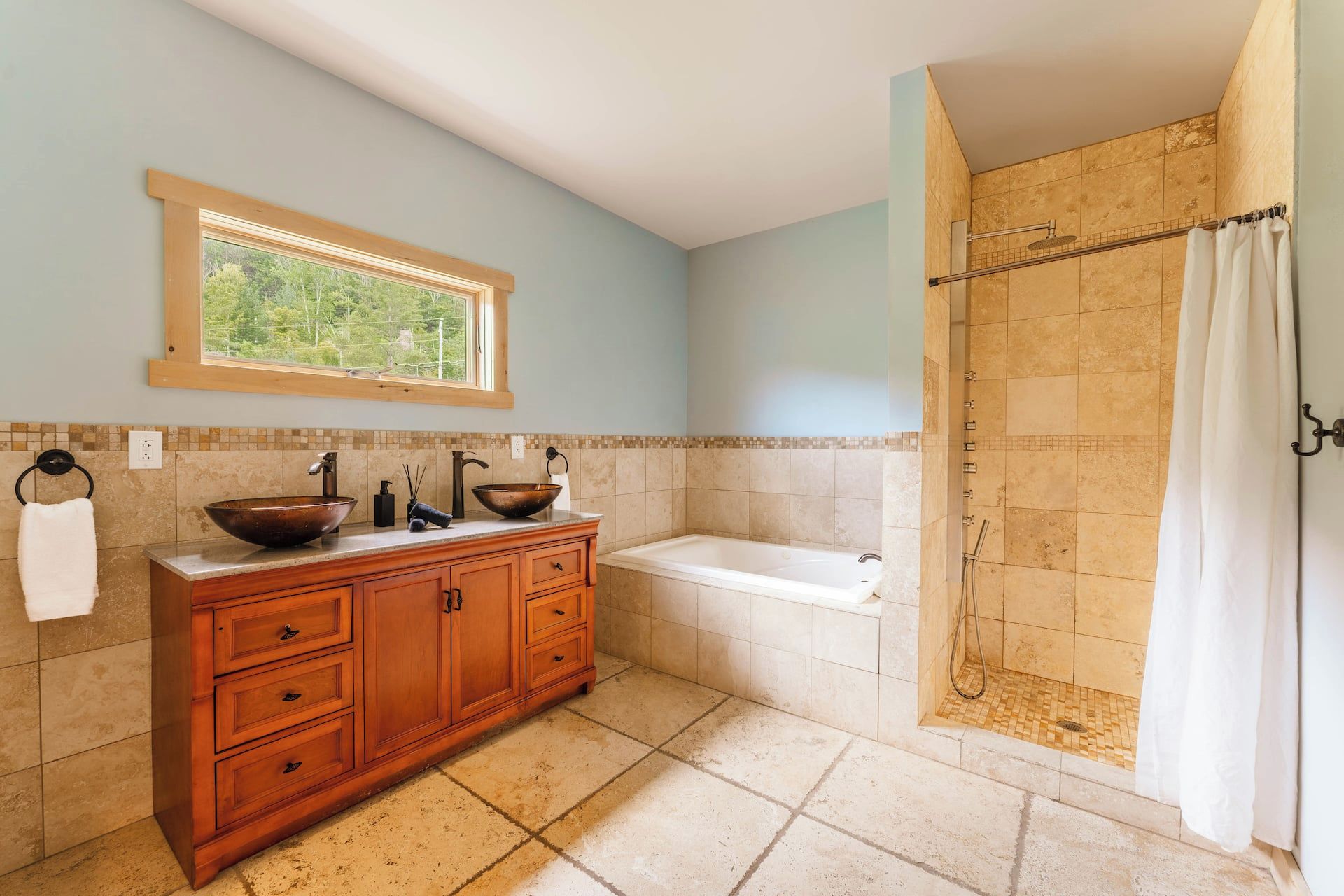 Une salle de bain avec un meuble-lavabo en bois, un grand lavabo, une baignoire et un espace douche.