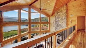 A spacious room with large windows offering views of a lake and mountains. - The Hunter Chalet (Hunter)