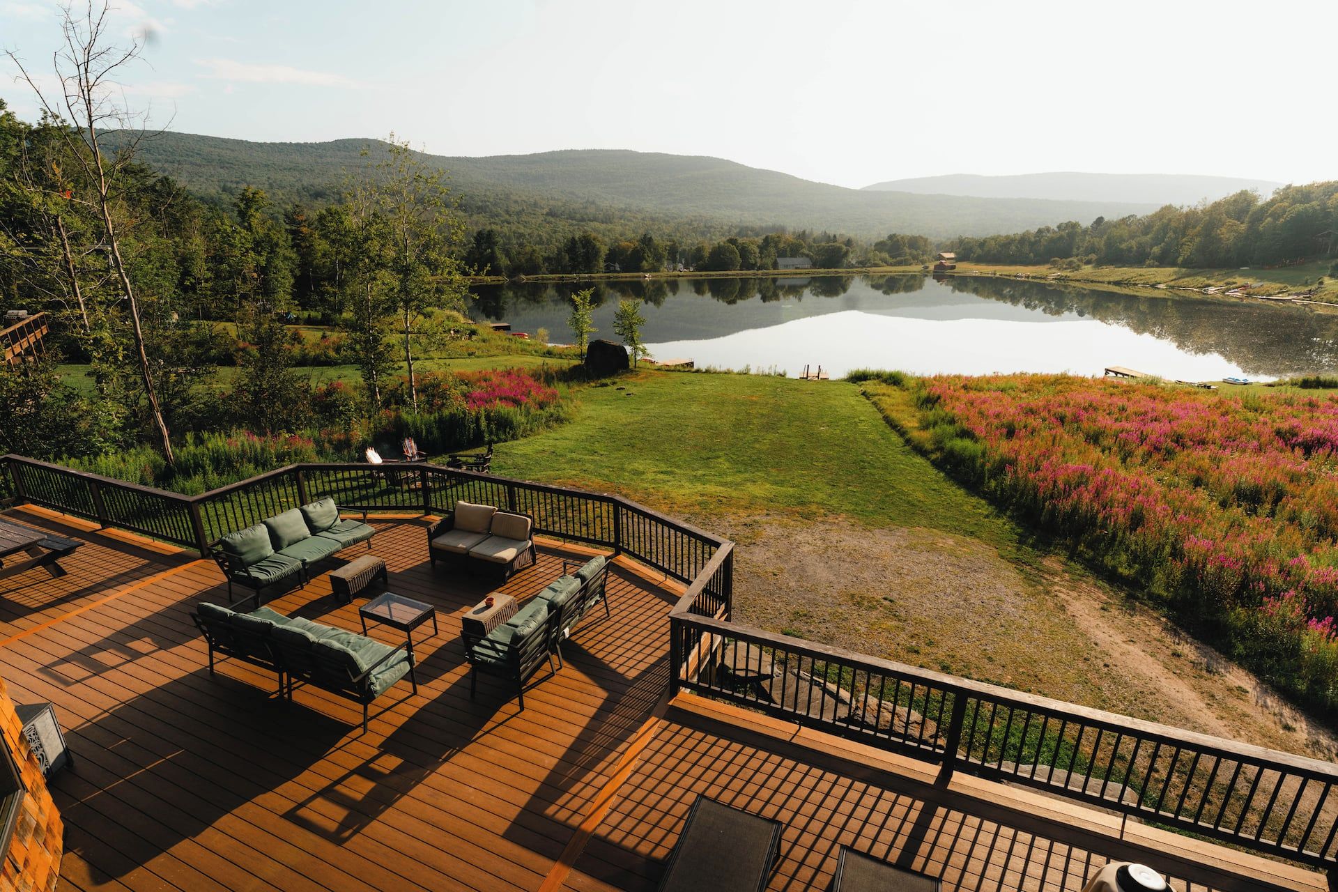 Une terrasse dotée de mobilier d’extérieur, offrant une vue sur un lac et des collines.
