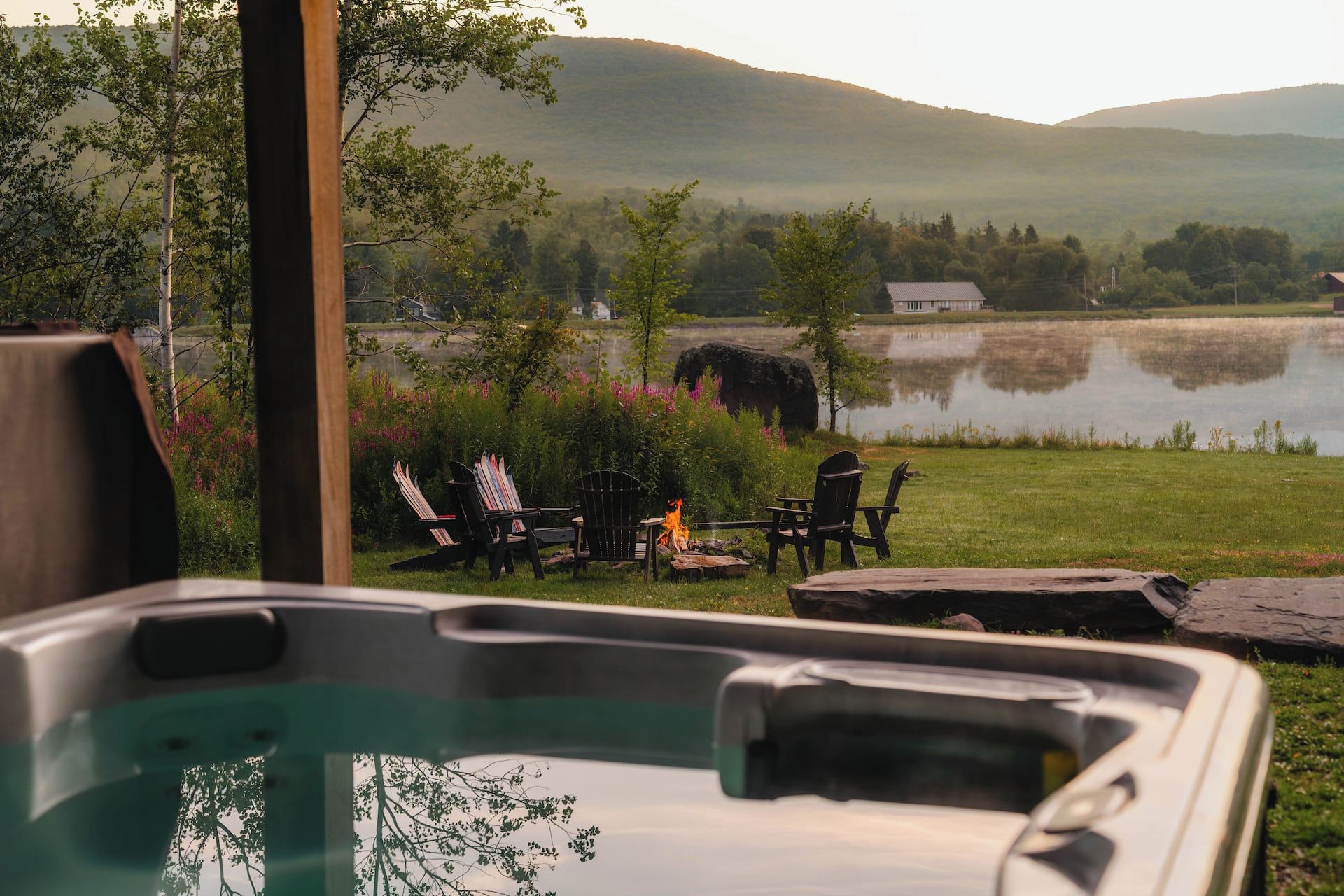 Un bain à remous avec vue sur un lac, des chaises et un foyer extérieur.