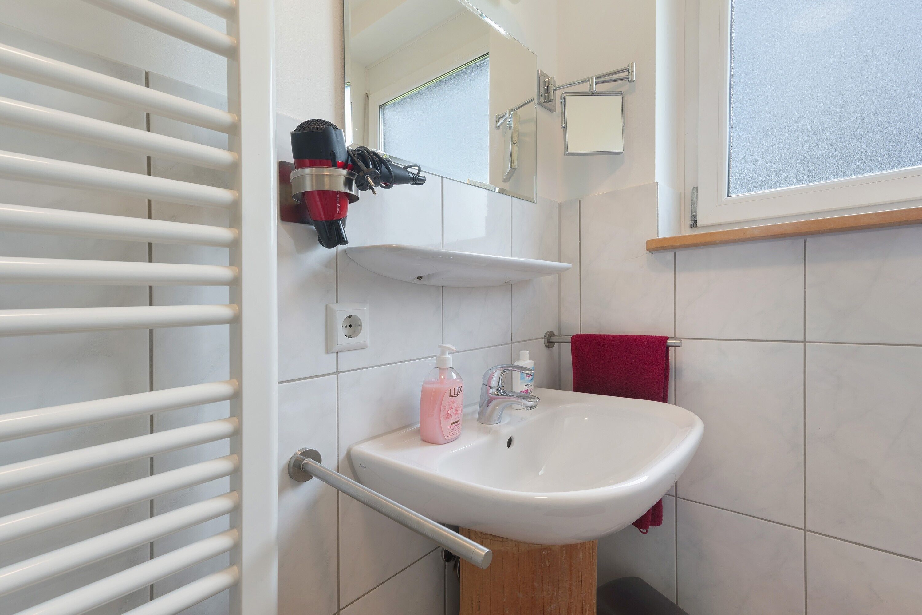 Ein Badezimmer mit einem weißen Waschbecken, einem Spiegel, einem Handtuchhalter und einem Handtuch.