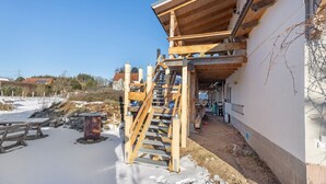 A wooden staircase leading to a covered outdoor area with a white wall and a clear blue sky. - Apartment 'Fewo Am Flämingrand' with Shared Garden, Balcony and Wi-Fi (Zahna-Elster)