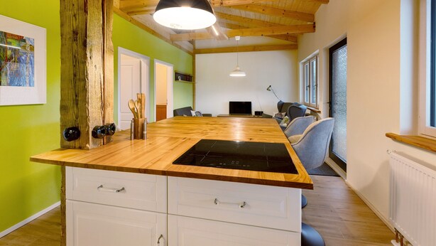 A kitchen with a wooden countertop, white cabinets, and a black induction cooktop. - Apartment 'Fewo Am Flämingrand' with Shared Garden, Balcony and Wi-Fi (Zahna-Elster)