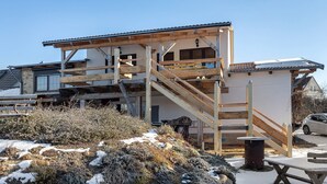 A building with a wooden deck, a staircase, and a table. - Apartment 'Fewo Am Flämingrand' with Shared Garden, Balcony and Wi-Fi (Zahna-Elster)