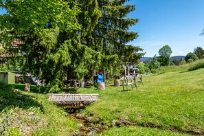 Un cadre extérieur rustique, avec une structure en bois, un petit ruisseau et une végétation luxuriante.