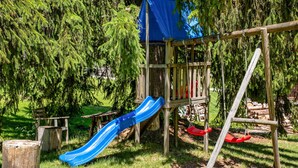 A playground with a blue slide, a swing set, and a wooden structure. - Apartment 'Fingerhut' with Mountain View, Private Terrace and Wi-Fi (Feldberg (Schwarzwald))