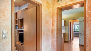 A hallway with wooden cabinets, a television, and a door leading to a kitchen area. - Apartment 'Fingerhut' with Mountain View, Private Terrace and Wi-Fi (Feldberg (Schwarzwald))