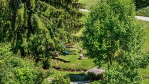 A rural landscape with a small wooden structure, a stone pathway, and dense greenery. - Apartment 'Fingerhut' with Mountain View, Private Terrace and Wi-Fi (Feldberg (Schwarzwald))