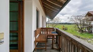 Eine Holzterrasse mit Bank und Tisch, mit Blick auf eine grüne Landschaft.