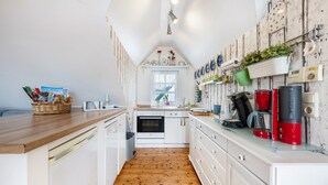 Une cuisine compacte avec des meubles blancs, un plancher en bois et divers appareils de cuisine et éléments de décoration.