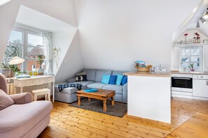 Ein modernes Wohnzimmer mit Sofa, Couchtisch und einer kleinen Essecke.