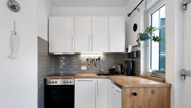 A modern kitchen with white cabinets, a wooden countertop, a stove, and a dishwasher. - Holiday Apartment 'Tu Huus' with Private Garden and Wi-Fi (Wesselburen)