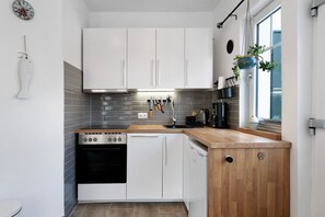 Une cuisine moderne avec des meubles blancs, un plan de travail en bois, une cuisinière et un lave-vaisselle.