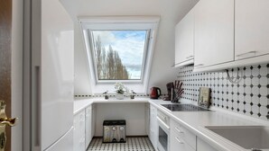 A compact kitchen with white cabinets, a window with a view, a tiled backsplash, and a sink. - Apartment 'Untersee' with Lake View, Private Terrace and Wi-Fi (Moos)