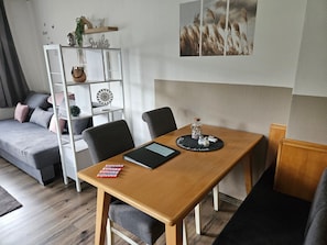 Un salon moderne avec une table à manger en bois, un canapé gris et une étagère blanche.