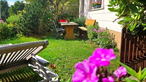 A garden with a wooden bench, a table, and a chair.