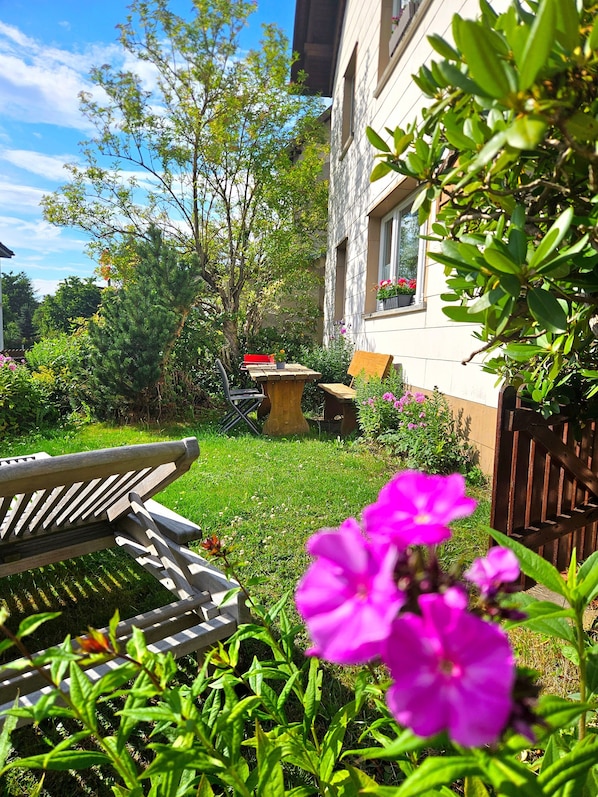 Un jardin avec un banc en bois, une table et une chaise.
