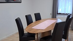 Una sala conferenze con un tavolo di legno, sedie nere, un sottopiatti rosa e un quadro appeso al muro.