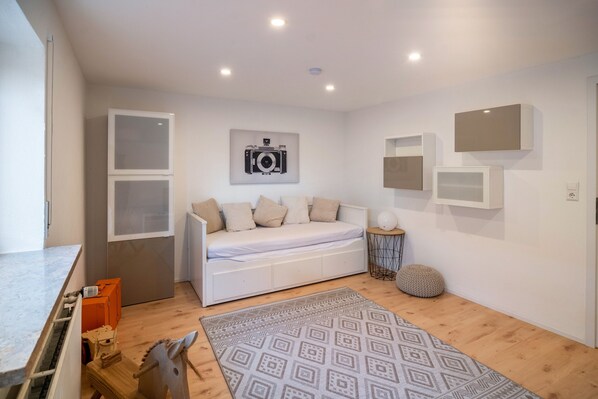 A modern room with a white sofa, a patterned rug, and a camera on the wall.