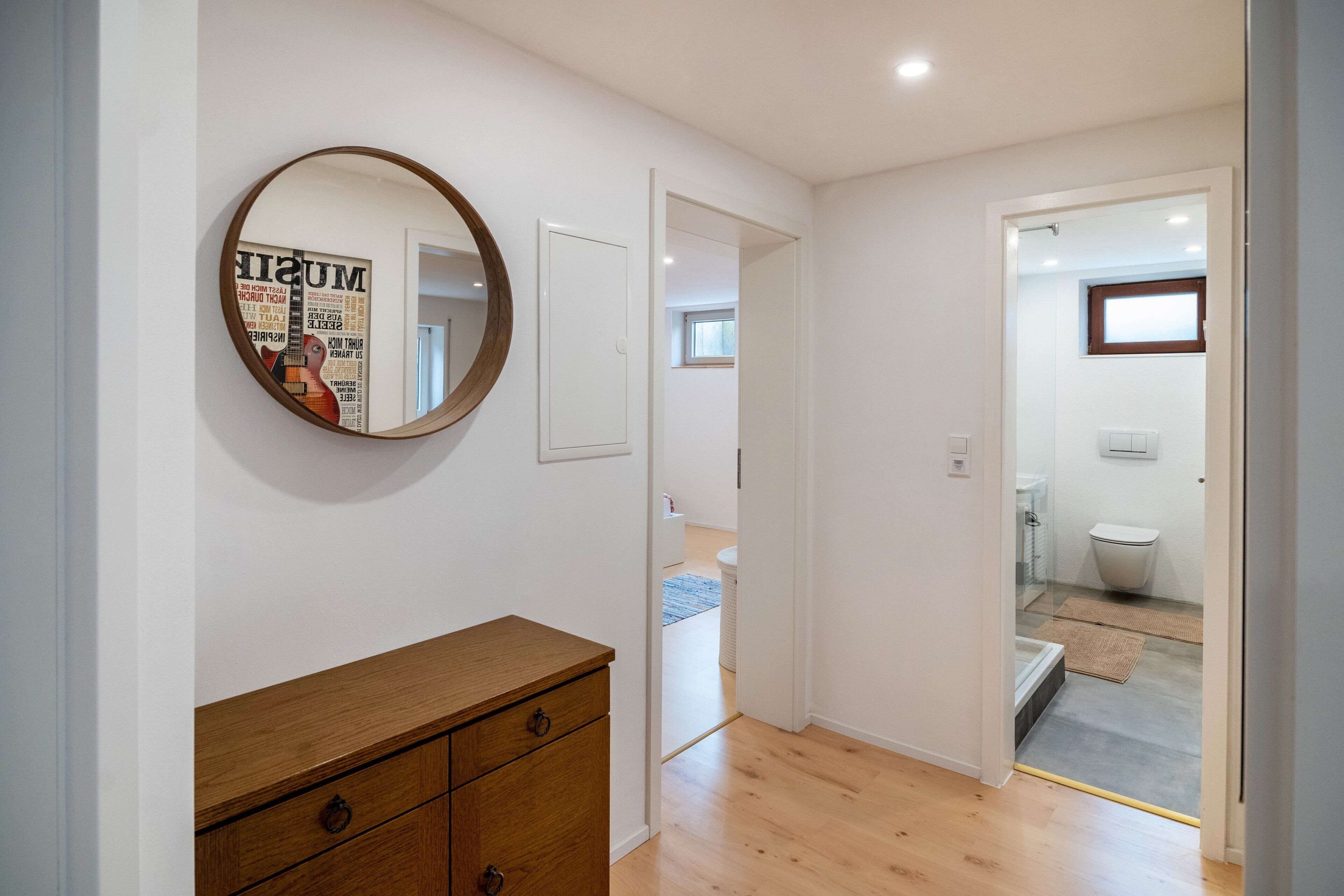 Pasillo que conduce a un baño con inodoro, ducha y ventana.