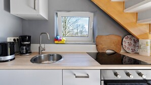 Una cocina con un lavamanos, estufa y ventana con vistas a un paisaje nevado.