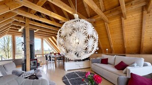 Amplia sala de estar con techo alto, vigas de madera, chimenea y un gran candelabro.