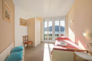 Quarto de hotel com uma cama, uma cadeira, uma mesa e vista para o exterior.
