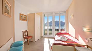 Una camera d'albergo con un letto, una sedia, un tavolo, una finestra vista e una porta che conduce a un'altra stanza.