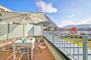 A balcony with a table, chairs, and a large umbrella. - Sogno Sul Lago  Lake Front, Laveno Mombello, Italy (Laveno Mombello)