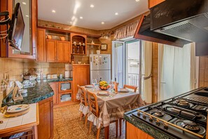 A kitchen with wooden cabinets, a dining table set for four, a stove, and a refrigerator.