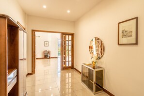 A hallway with a wooden cabinet, a glass cabinet with a mirror, and a framed picture on the wall.
