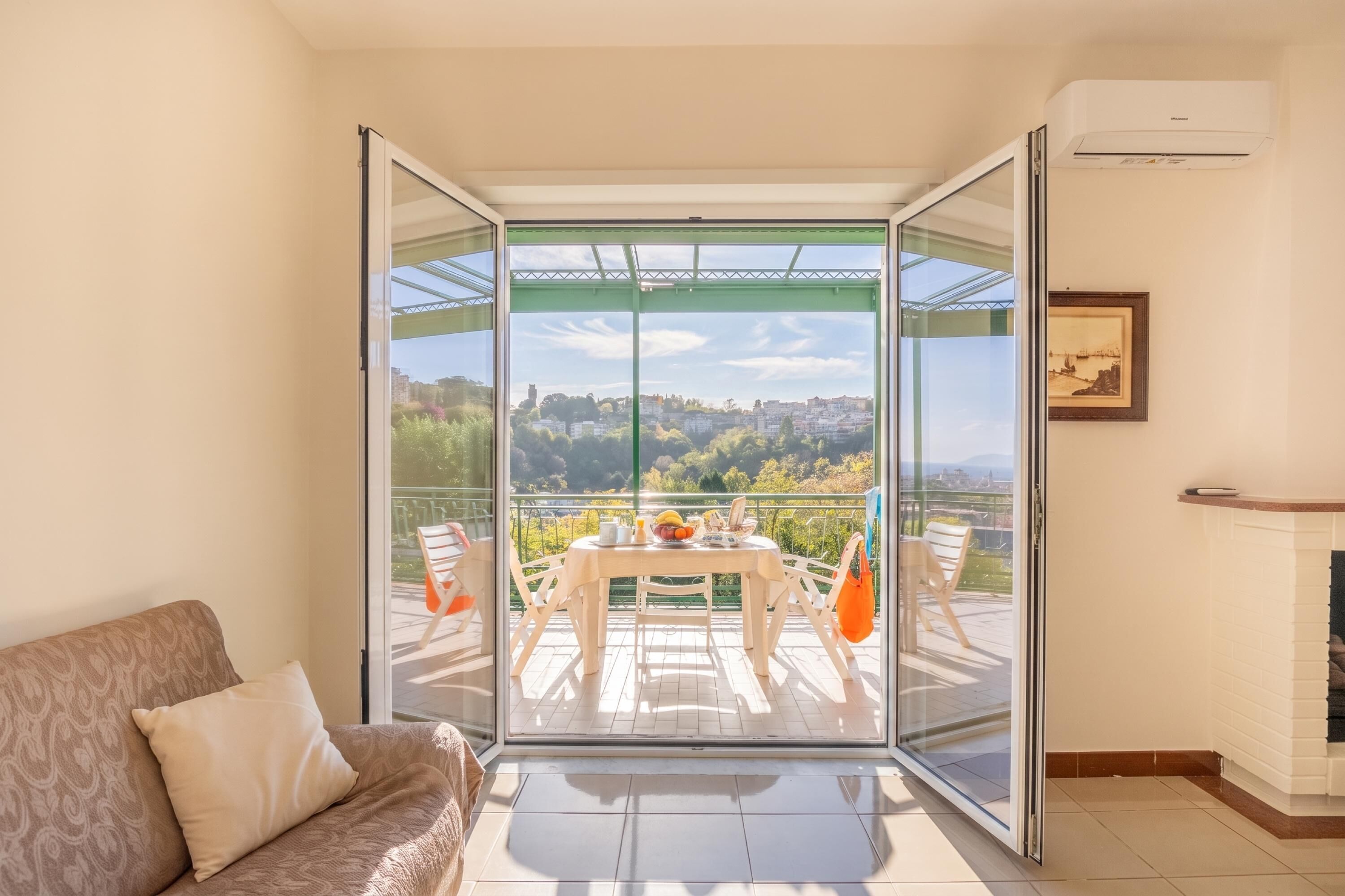 Una habitación con puerta de vidrio que da a un patio exterior con mesa y sillas, un sofá y una chimenea.