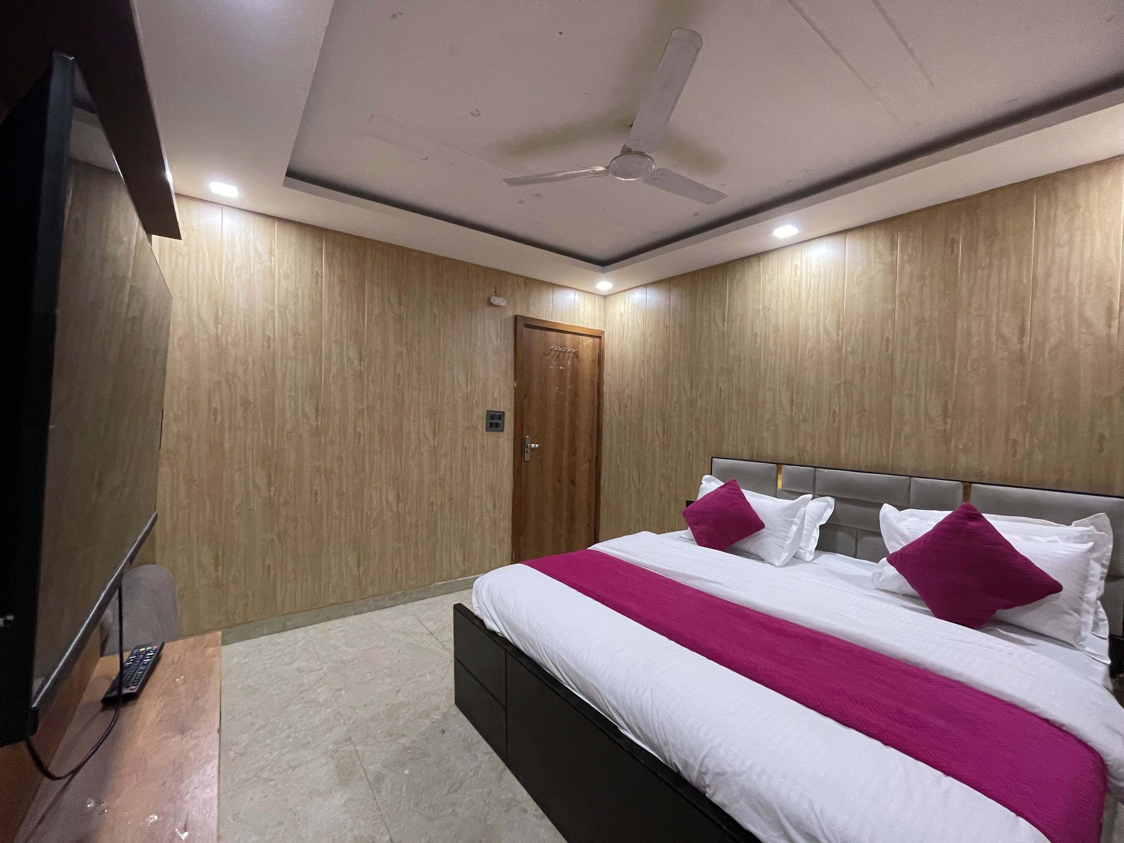 Ein Hotelzimmer mit einem Bett, einem Fernseher und einem Deckenventilator.