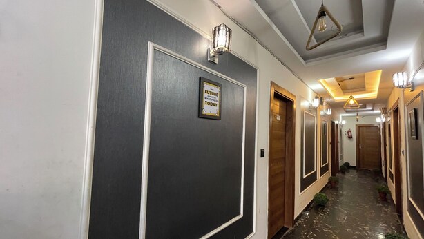 Pasillo de hotel con paredes oscuras, molduras blancas y una cita inspiradora enmarcada.