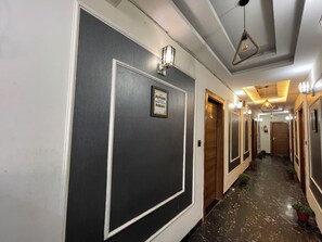 A hotel corridor with dark walls, white trim, and a framed inspirational quote. - Hotel Heaven  Pacific Mall Subhash Nagar (New Delhi)