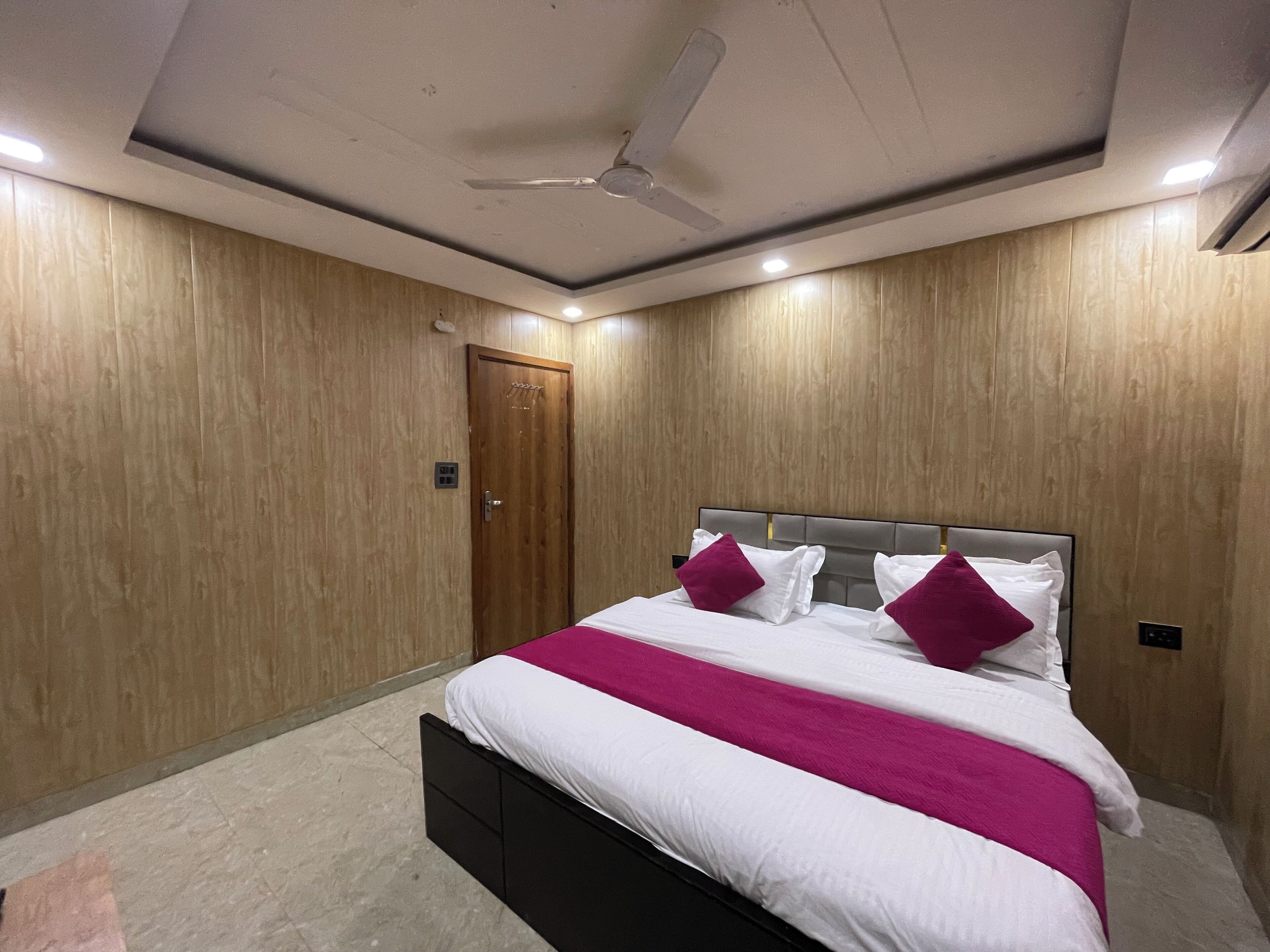 Une chambre à coucher avec un lit, des murs en bois, un ventilateur de plafond et des luminaires encastrés.