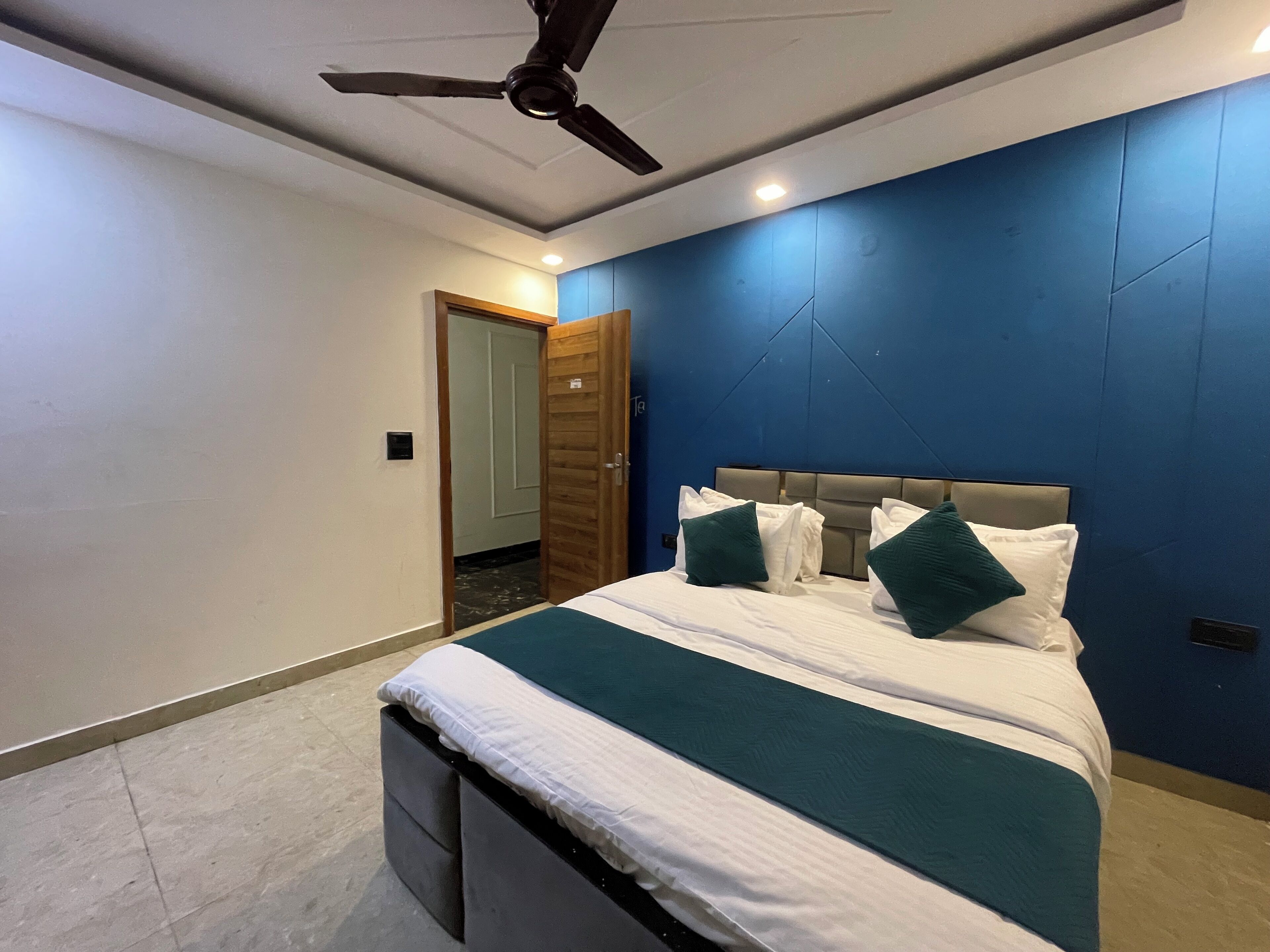 A modern bedroom with a bed, a ceiling fan, and a door leading to another room.