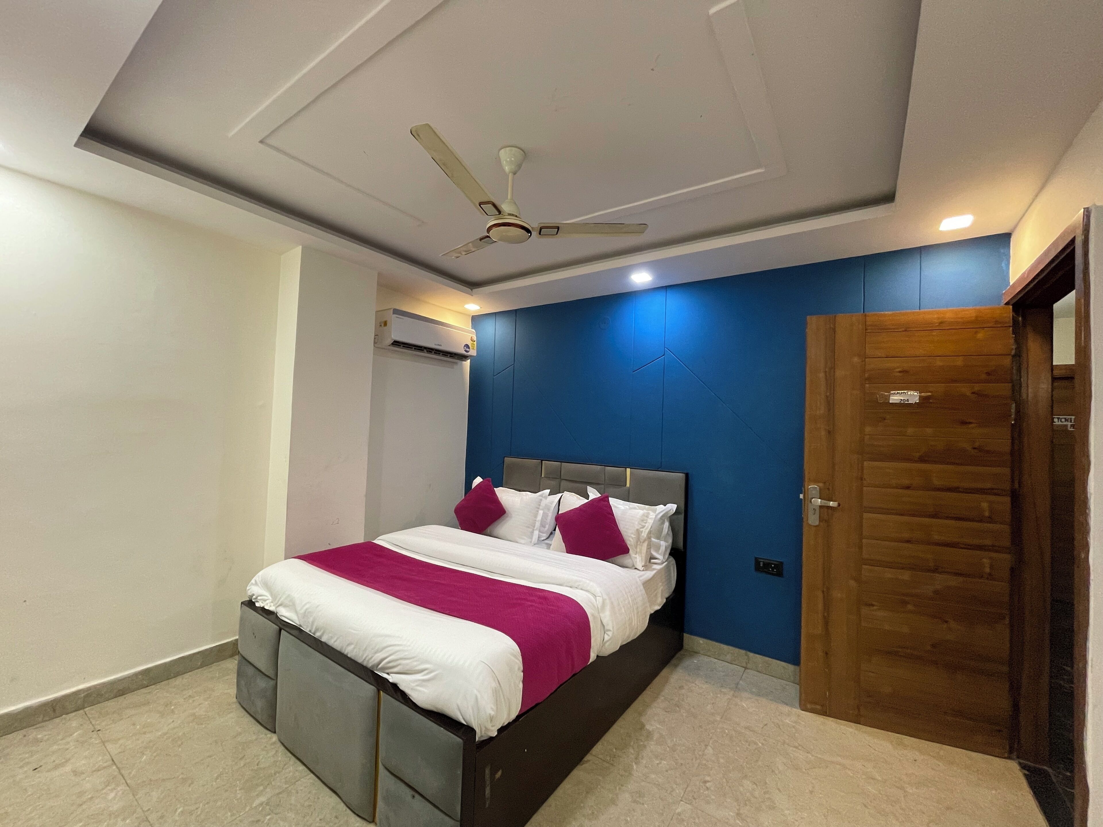 A modern bedroom with a bed, a ceiling fan, and a wooden door.