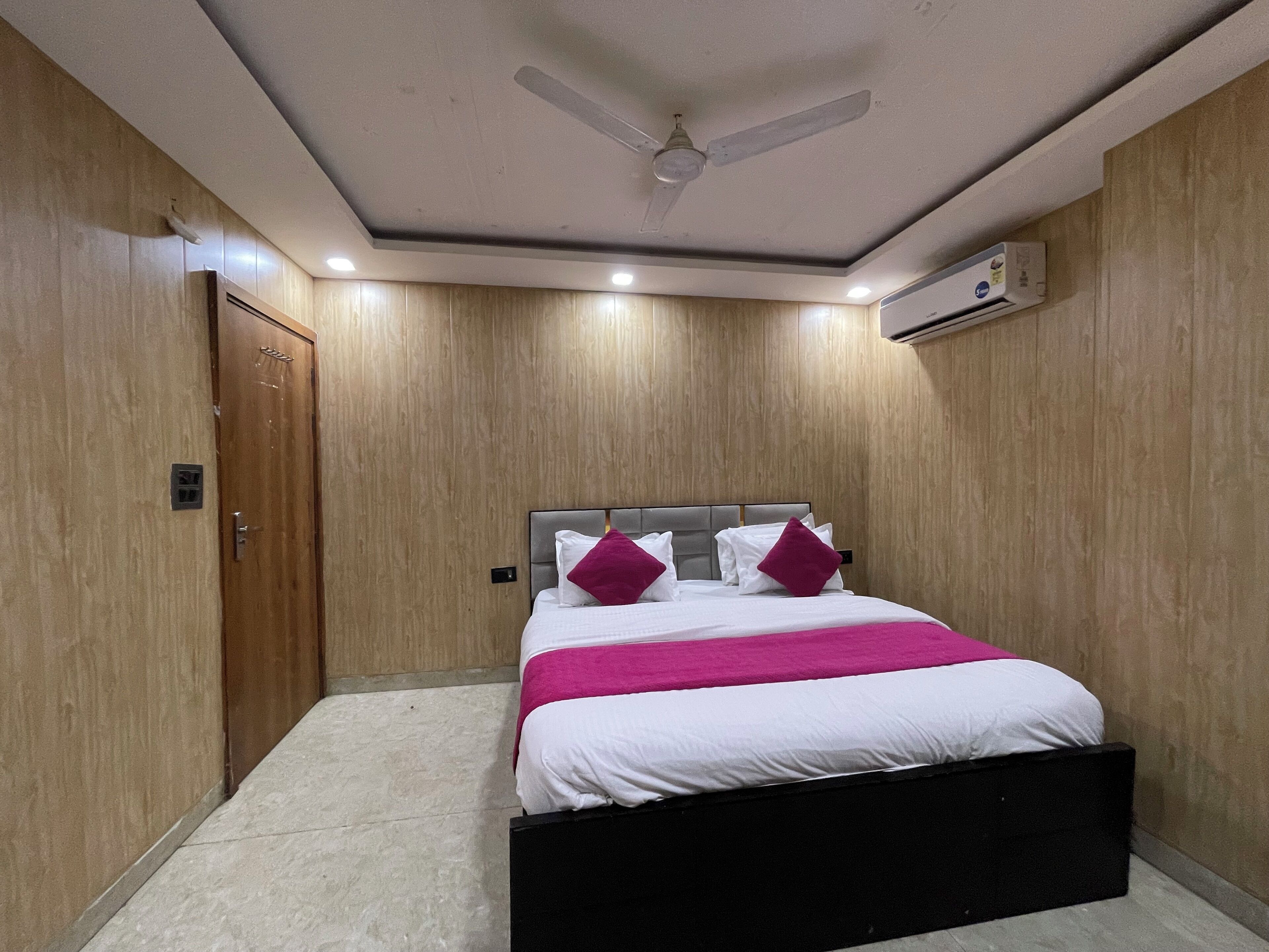 Ein Schlafzimmer mit einem Bett, einem Deckenventilator, einer Klimaanlage und Holzwänden.