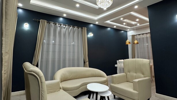 A modern living room with a sofa set, a coffee table, and a chandelier. - Luxury home,  located in a quiet and calm area, Home away from home. (Entebbe)