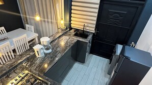 A compact kitchen with a gas stove, sink, and modern appliances. There is a dining area with a table and chairs, and a window with curtains. - Luxury home,  located in a quiet and calm area, Home away from home. (Entebbe)